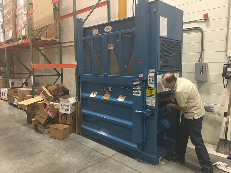 man operating blue vertical baler